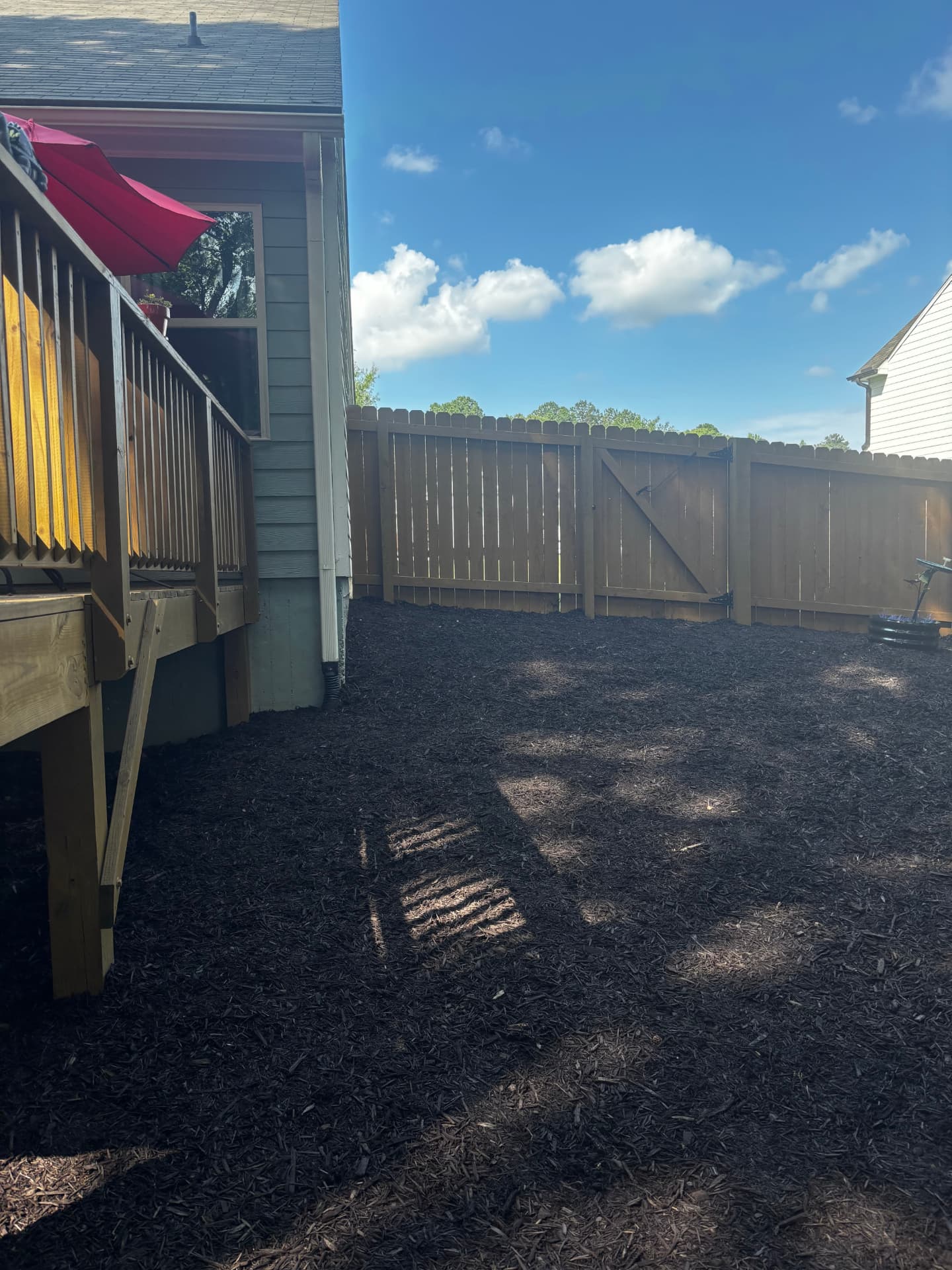 Clean mulched yard beside a deck and privacy fence
